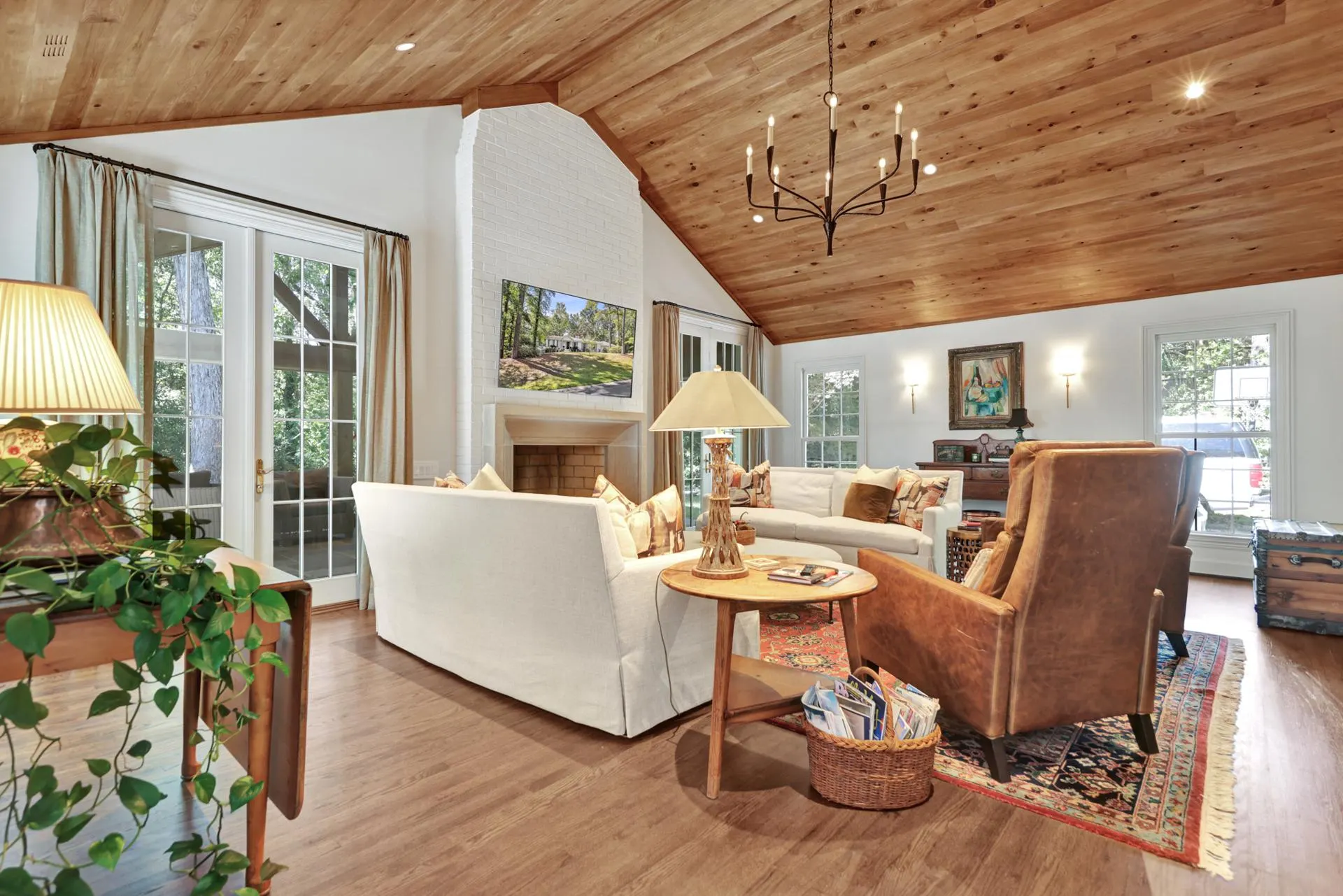 Renovated living room with a vaulted wood ceiling and painted brick fireplace